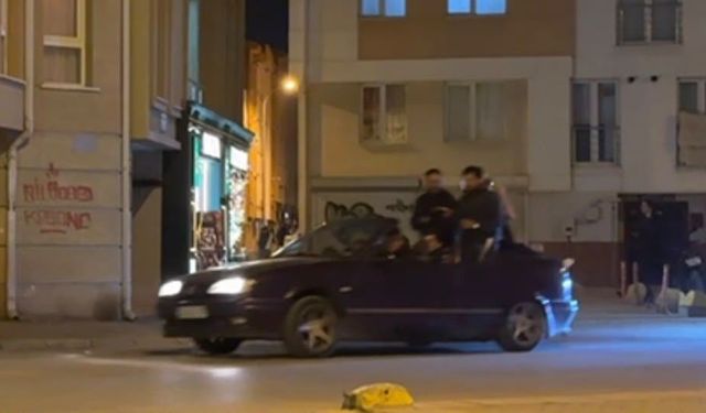 Seyir halindeki otomobillin bagajına ters oturan şahıs dikkat çekti