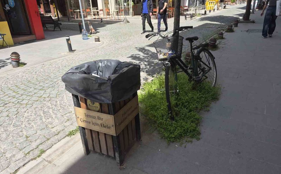 Çöp kutusunun hemen yanındaki bisikletin sepeti atıklarla doldu